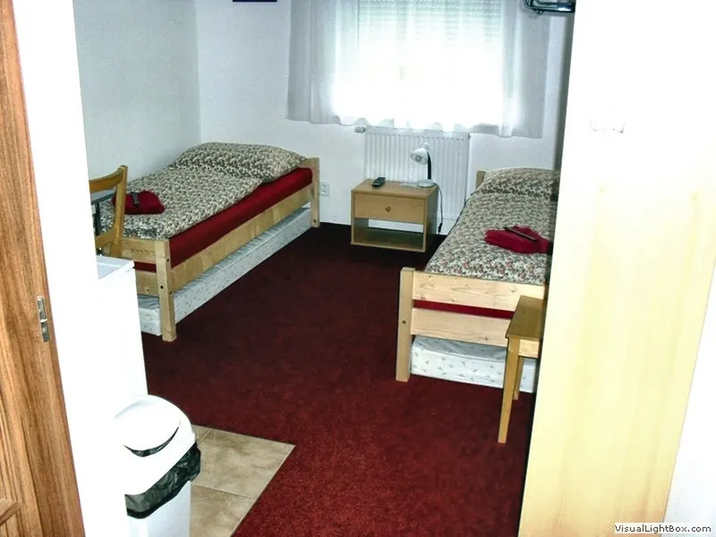 Dvoulůžkový pokoj se dvěma postelemi, nočním stolkem a oknem
